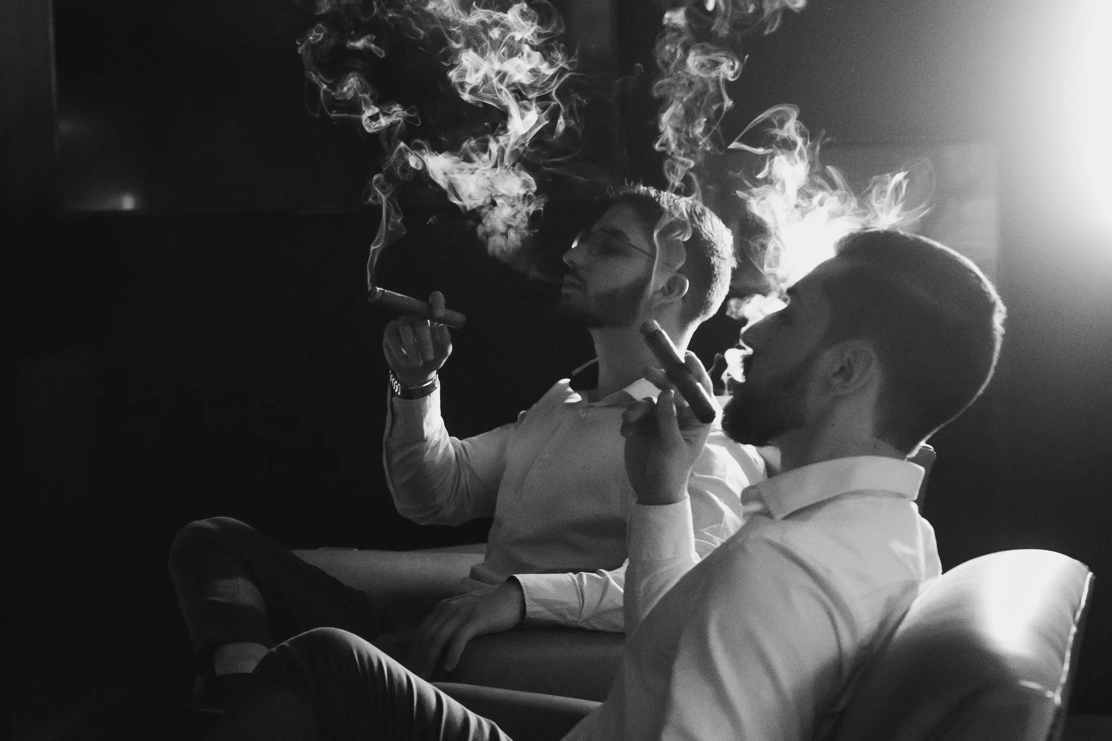 Dois apreciadores degustando charutos no lounge da IOSEPH, em preto e branco